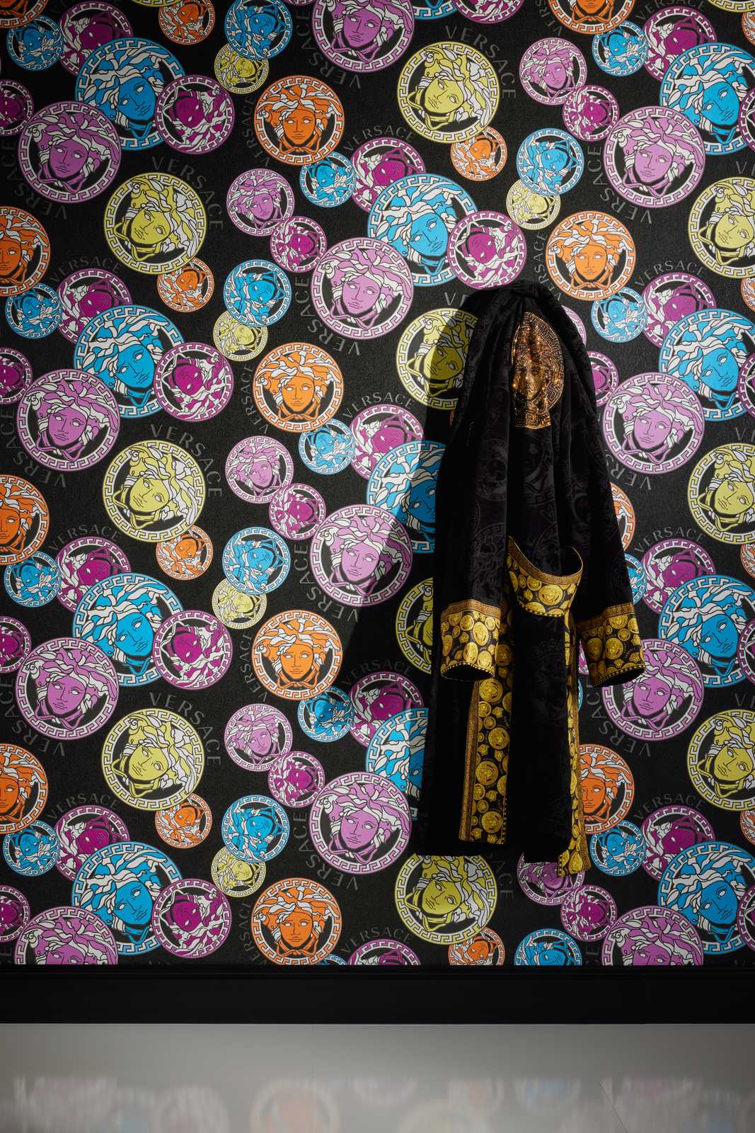             Black VERSACE wallpaper with colourful Medusa pattern
        